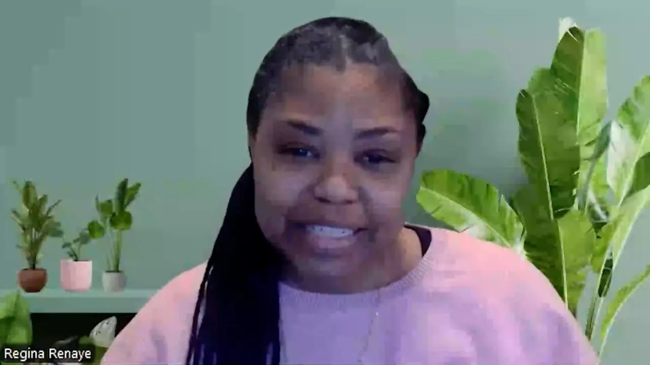 ```markdown
Person in pink sweater smiling, green plant background.
```