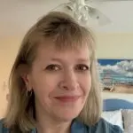 Smiling person in a casual setting with a beach-themed background decor.