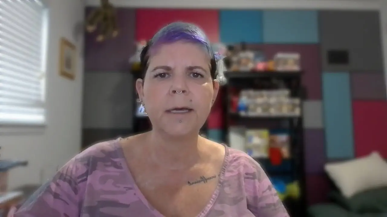Person with colorful hair and piercings in a creative home office setting.