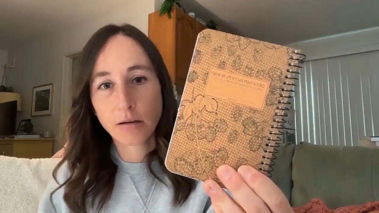 Person showing a decorative notebook with floral design in a cozy interior setting.