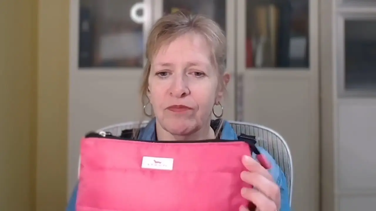 Person examining a pink pouch with focus, indoors.