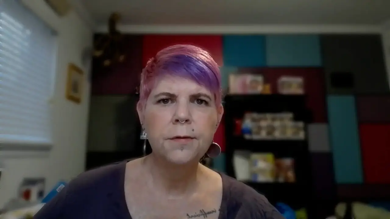 Person with colorful hairstyle in a stylish room with a focus on facial expression.